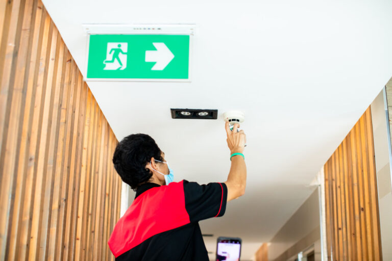 The technician is using smoke spray to check smoke detector of fire alarm system. Service center.